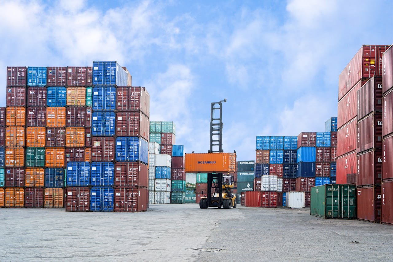 services-01 Colorful shipping containers and forklift in a busy Jakarta port under blue skies.